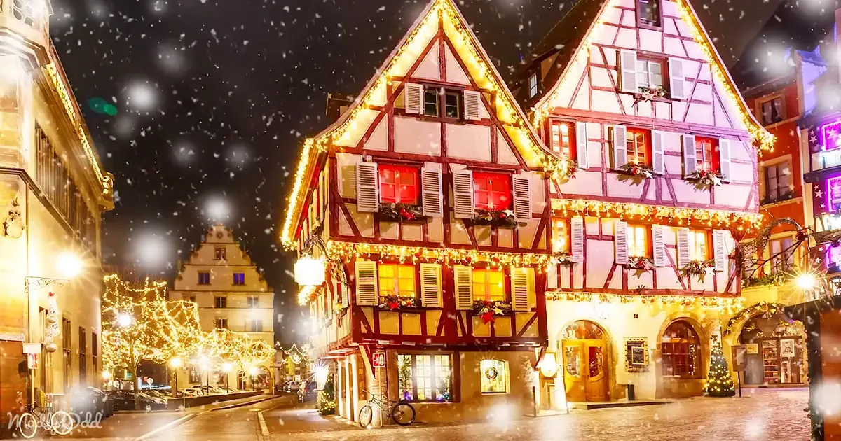 I see a beautifully lit, snow-covered half-timbered building adorned with festive decorations and lights.