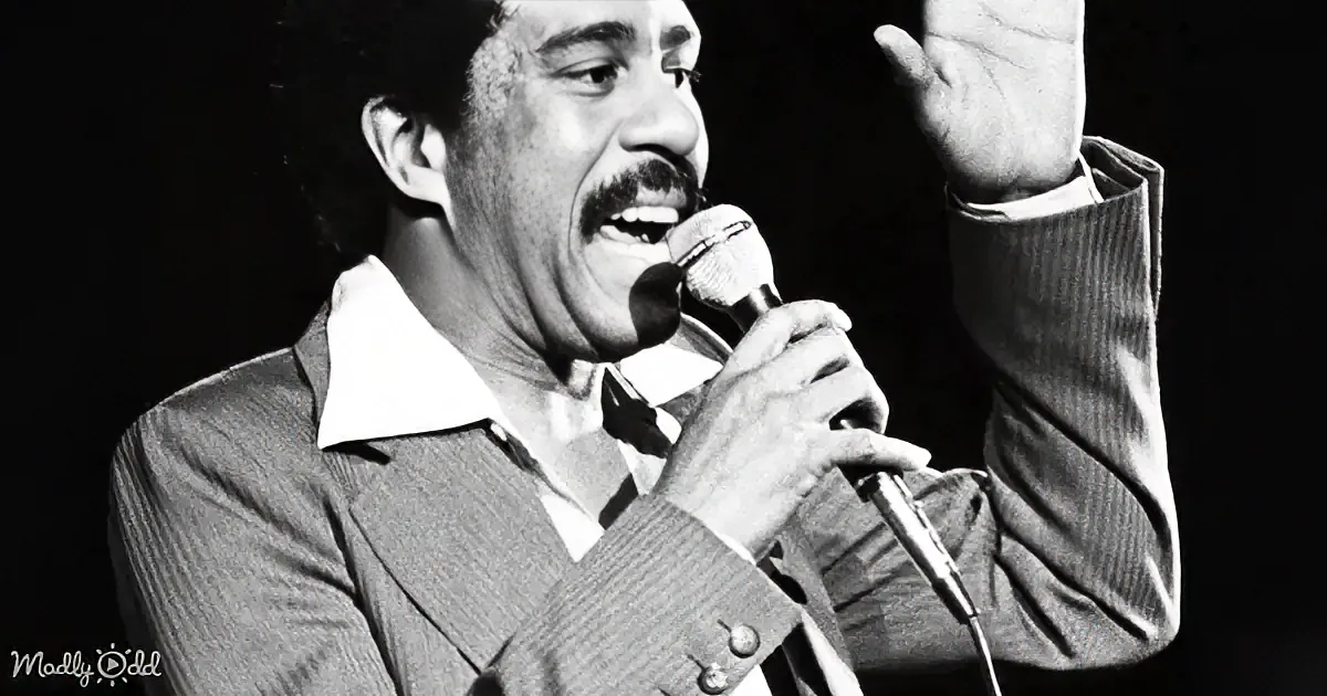 A man in a suit sings into a microphone, gesturing with his right hand.