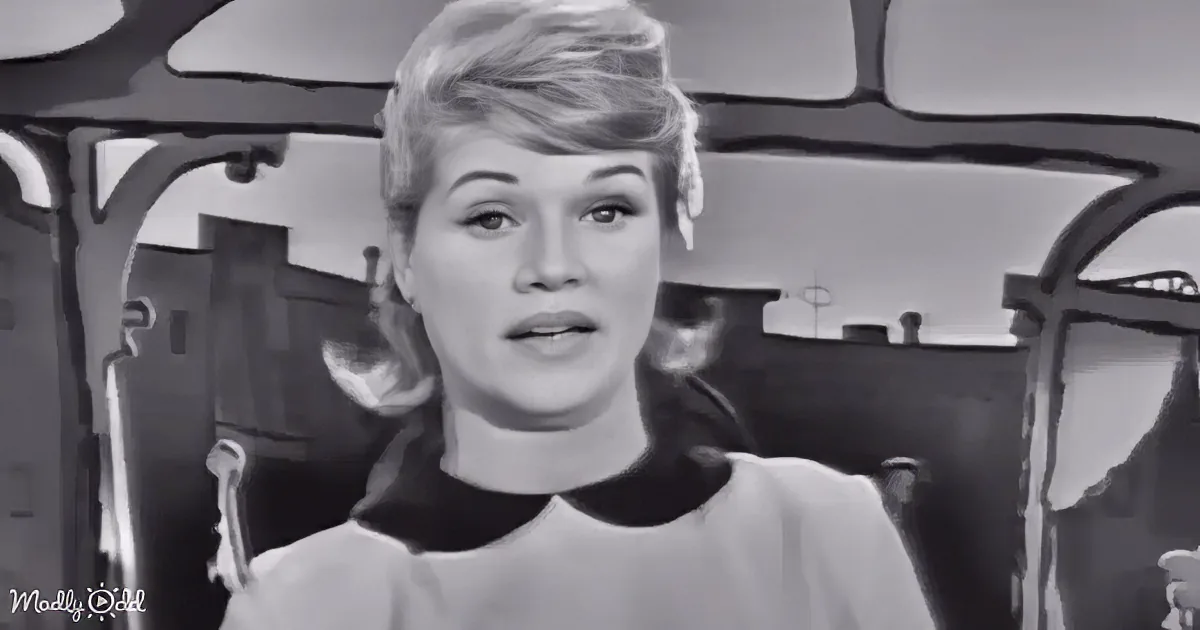 A woman with short hair and a surprised expression in a black-and-white scene.