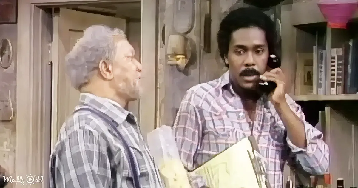 A man in a plaid shirt holds a phone to his ear while another man in a similar shirt looks on.