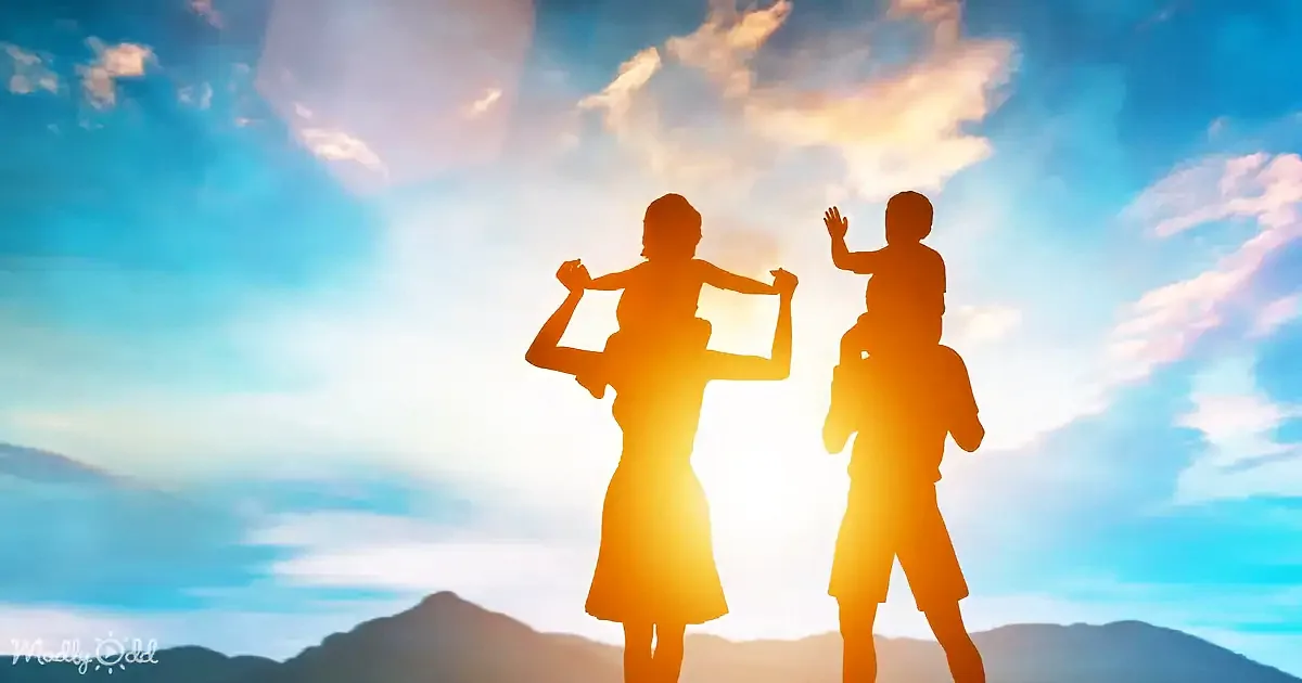 A silhouette of a woman carrying a child on her shoulders and a man carrying a child on his shoulders against a colorful sky.