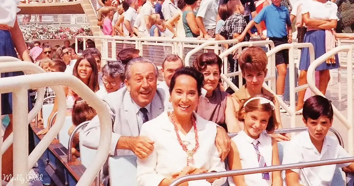 A family smiles together on a roller coaster ride, surrounded by other passengers.
