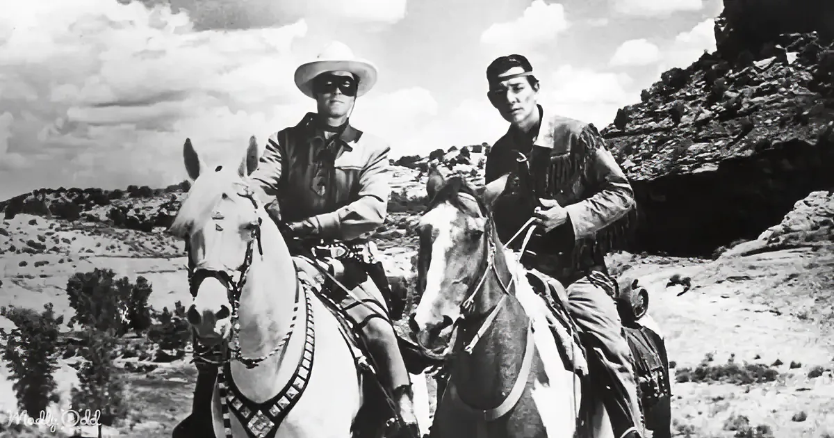 Two cowboys on horses in a desert landscape, one wearing a mask and hat.