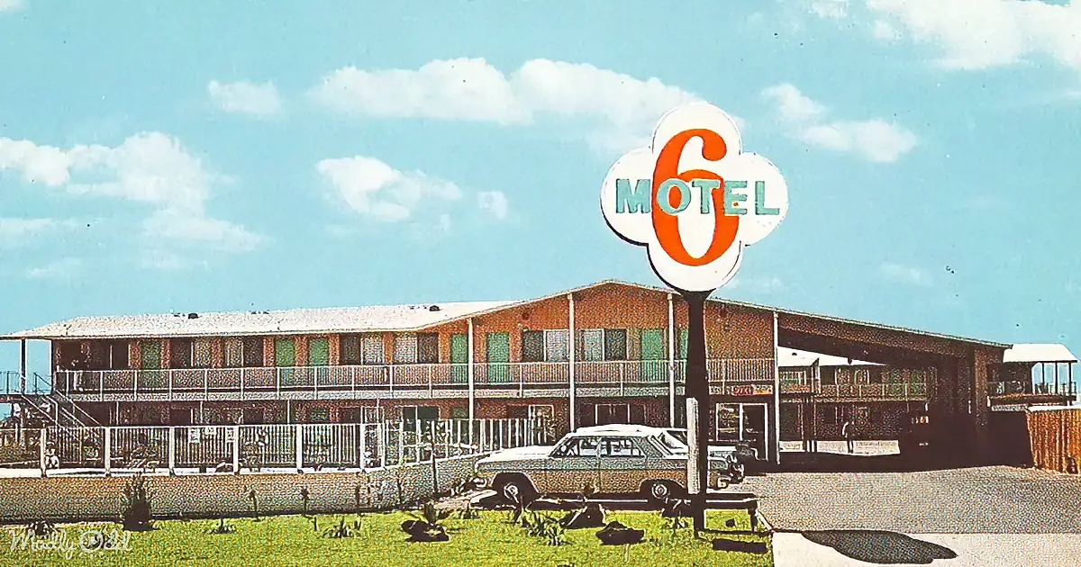 A vintage Motel 6 sign stands in front of a two-story motel with balconies and a classic car parked nearby.