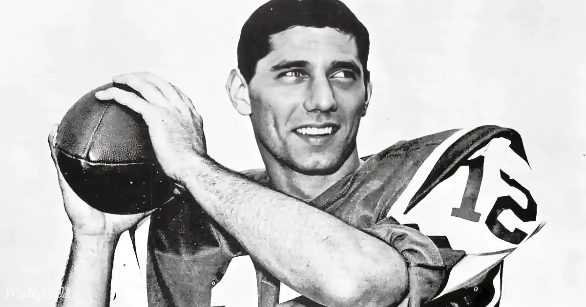 A man in a football uniform holds a ball, wearing a jersey with the number 12.