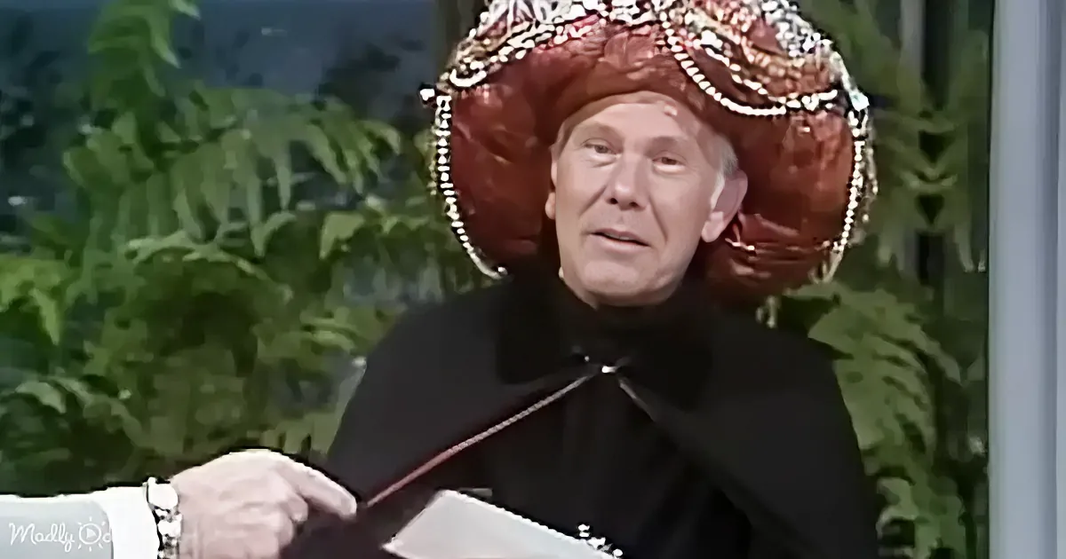 A man in a black outfit and ornate red hat is holding a piece of paper.