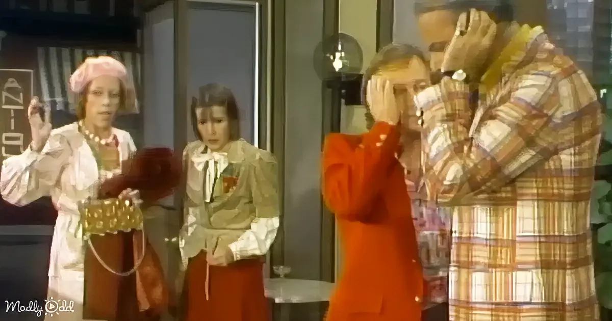 A man in a plaid shirt and a woman in an orange suit are covering their faces, seemingly distressed.