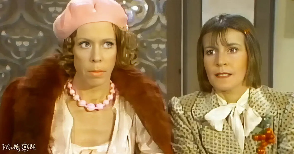 A woman in a pink beret and fur coat sits next to another woman in a patterned dress with a white bow.