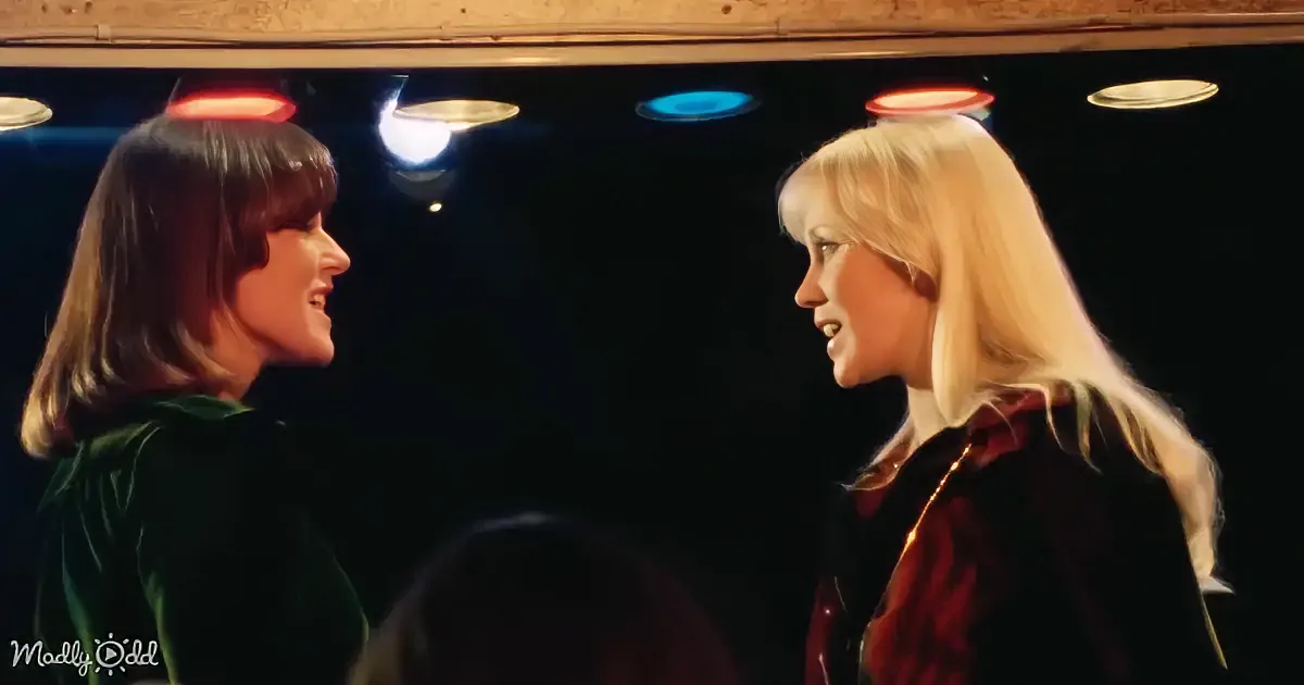 Two women with halo-like lights above their heads, one in green, one in red, facing each other.