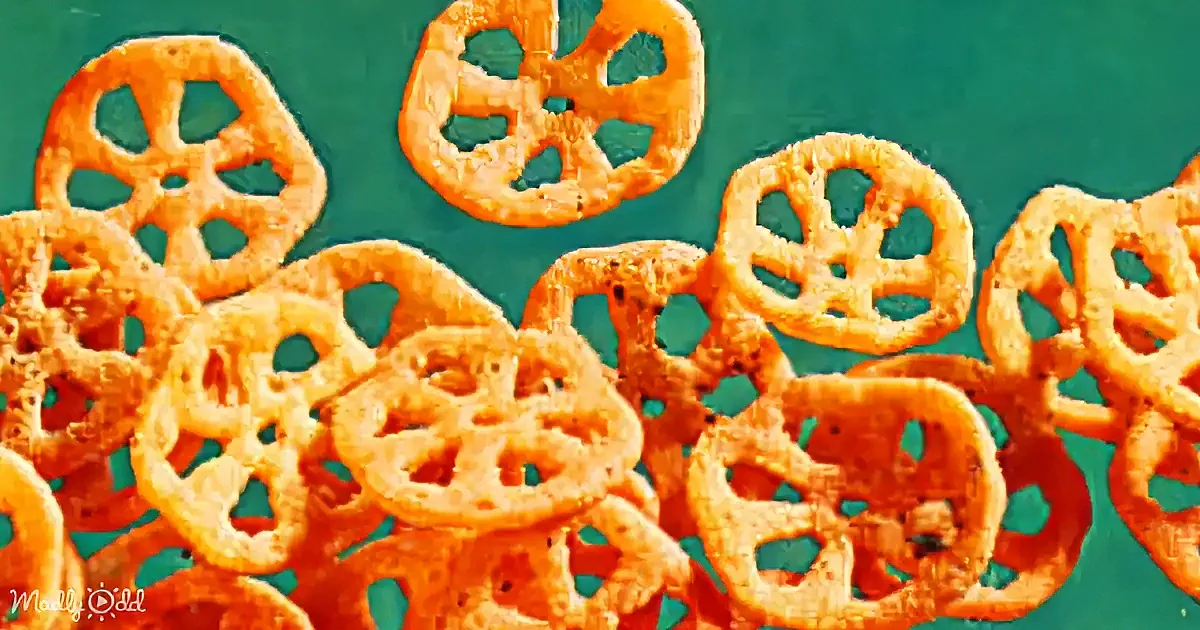 Golden pretzels with intricate holes on a vibrant teal background.
