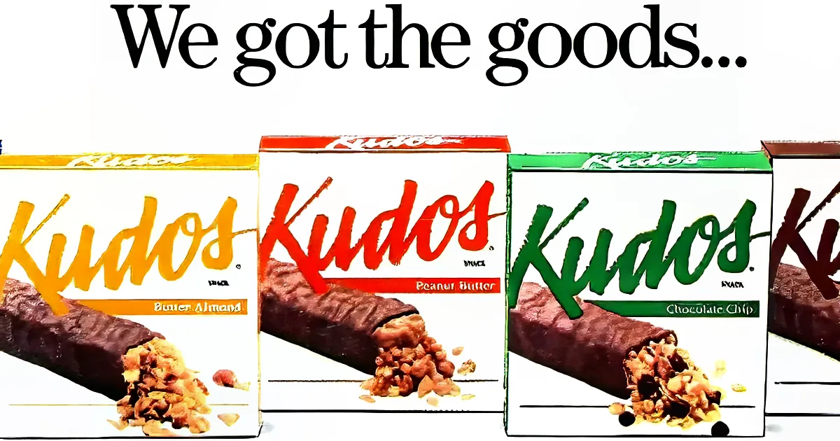 Kudos snack bars in Butter Almond, Peanut Butter, and Chocolate Chip flavors are displayed.