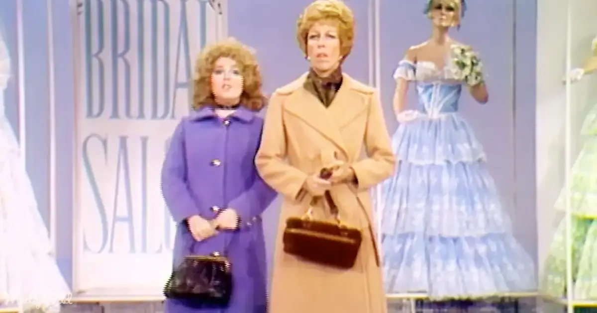 Two women in coats stand in front of bridal salon displays, one holding a purse.