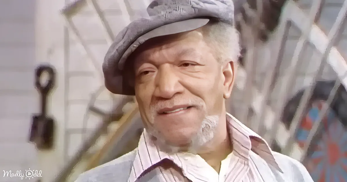 An older man wearing a flat cap and striped shirt smiles, with a blurred background of a house and ladder.