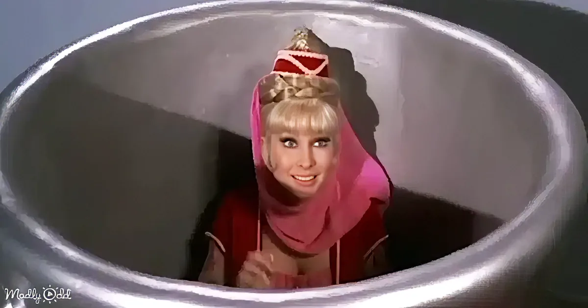 A person in a pink outfit and hat is peeking out from inside a large metallic bucket.