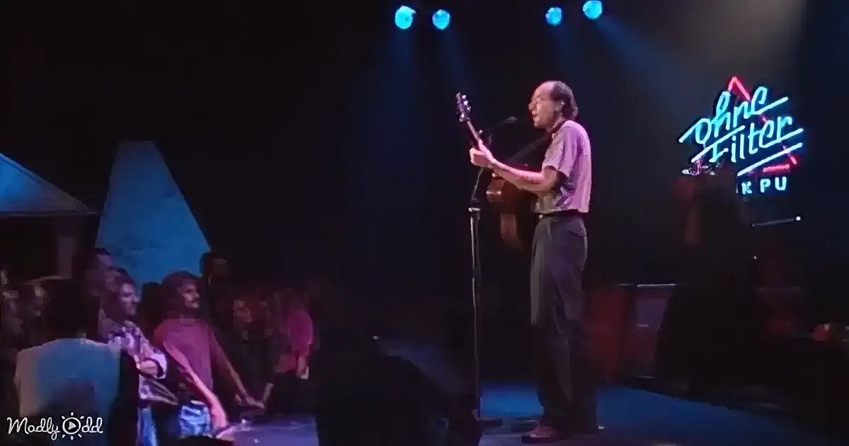 A person plays guitar on stage under blue lights, with a neon sign reading "Ohne Filter" in the background.
