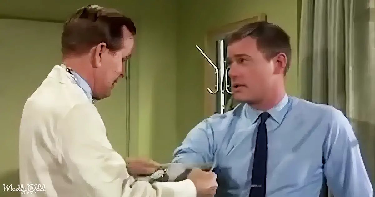 A man in a white coat is examining another man's wrist with a stethoscope.