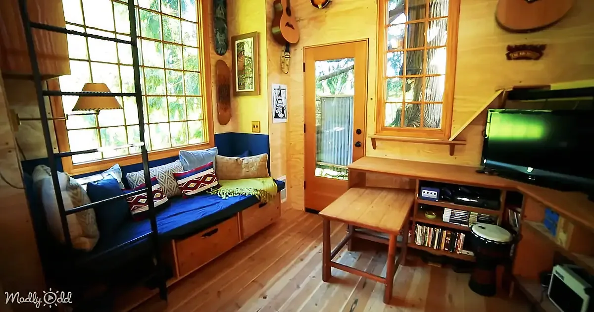 A cozy, rustic room with wooden furniture, a blue bench, and a TV, featuring a guitar and other musical decor.