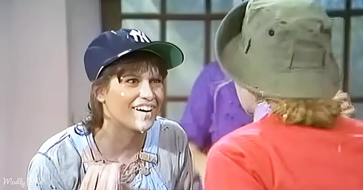 A person in a baseball cap smiles while talking to another person in a red shirt.