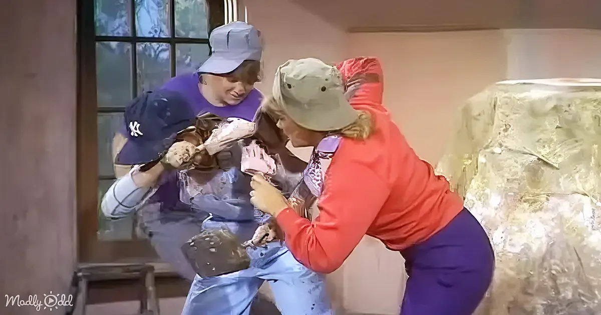 A person in a red shirt and cap is holding a hammer, seemingly about to hit another person in a purple shirt and cap.
