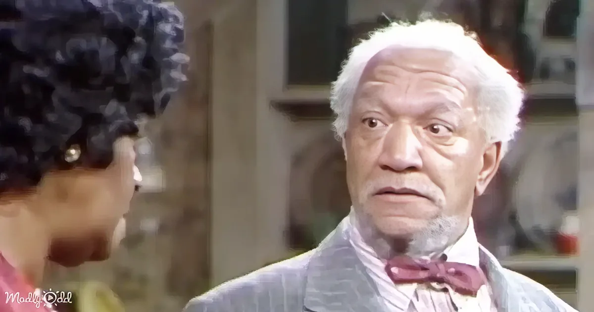 An older man in a suit and bow tie looks concerned while talking to a woman with curly hair.