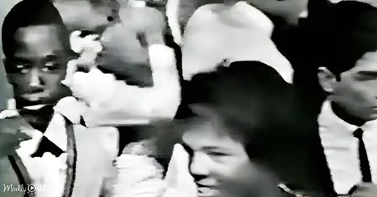 A young boy in a white shirt and tie is smiling, surrounded by other children in a classroom setting.