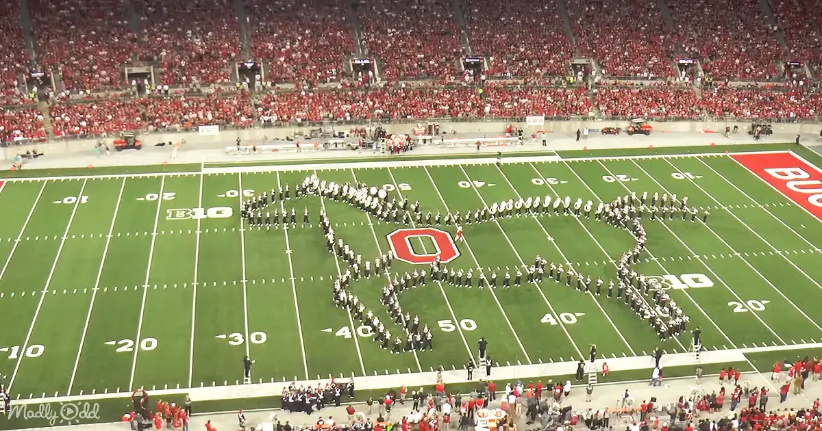 A marching band forms a large "O" on a football field during a game.