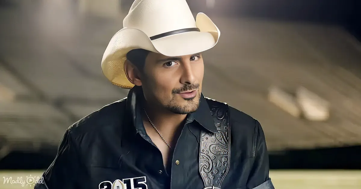 A man in a white cowboy hat and black shirt with intricate designs is looking to the side.