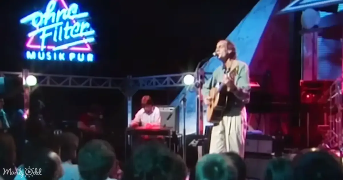 A man plays guitar on stage under neon "Ohne Filter Musik Pub" sign, audience in foreground.