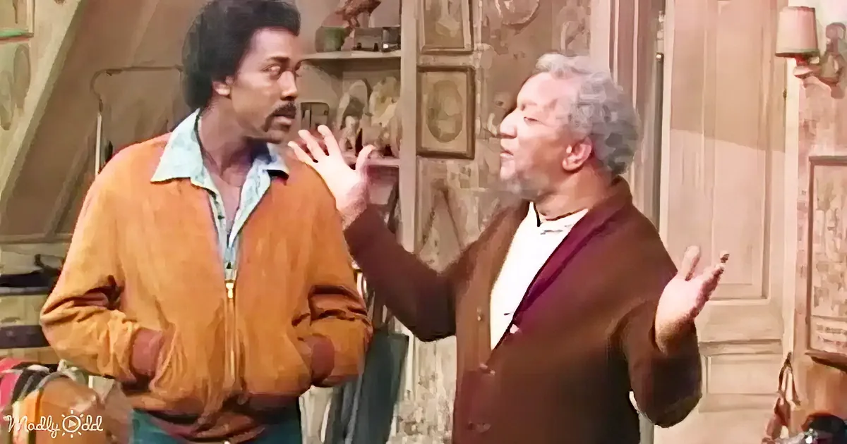 Two men in a room, one gesturing with his hands, another listening intently.