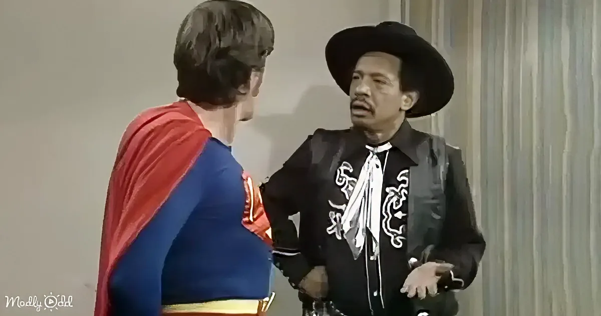 A man in a cowboy outfit stands next to a person in a Superman costume, both facing each other.