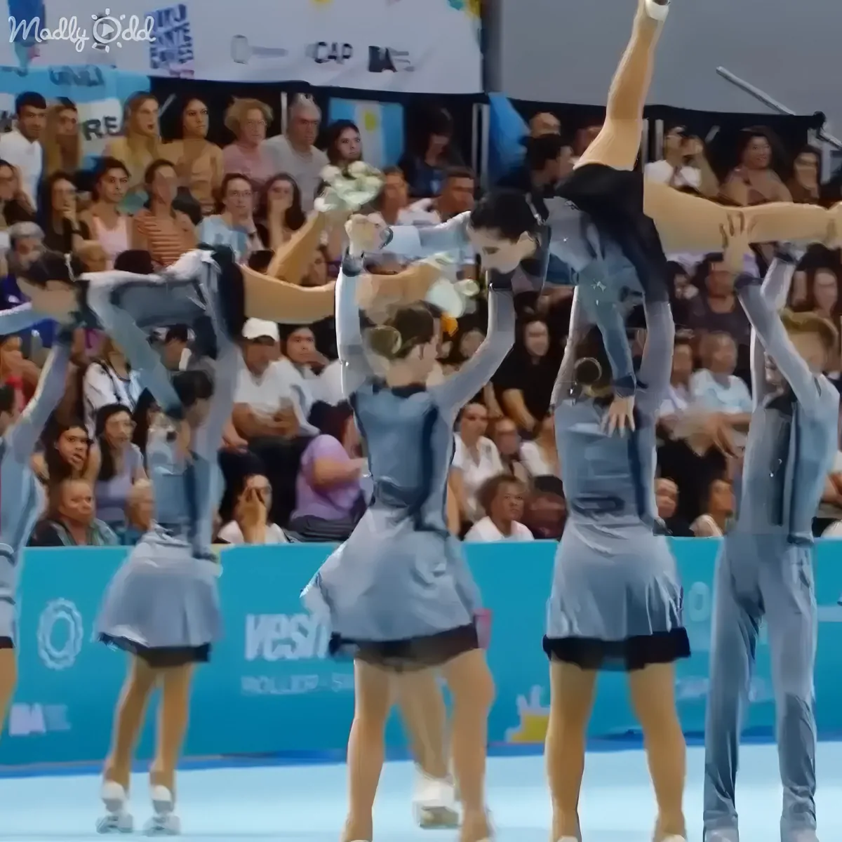 Cheerleaders performing a synchronized stunt with one member elevated above others in a blue and white uniform.