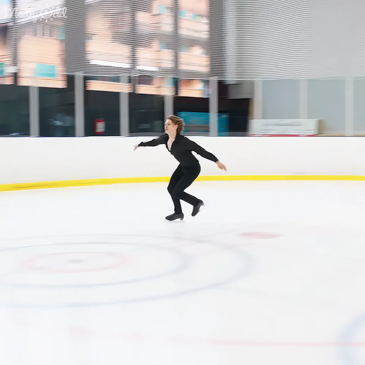 A figure skater in black attire glides gracefully on an ice rink.