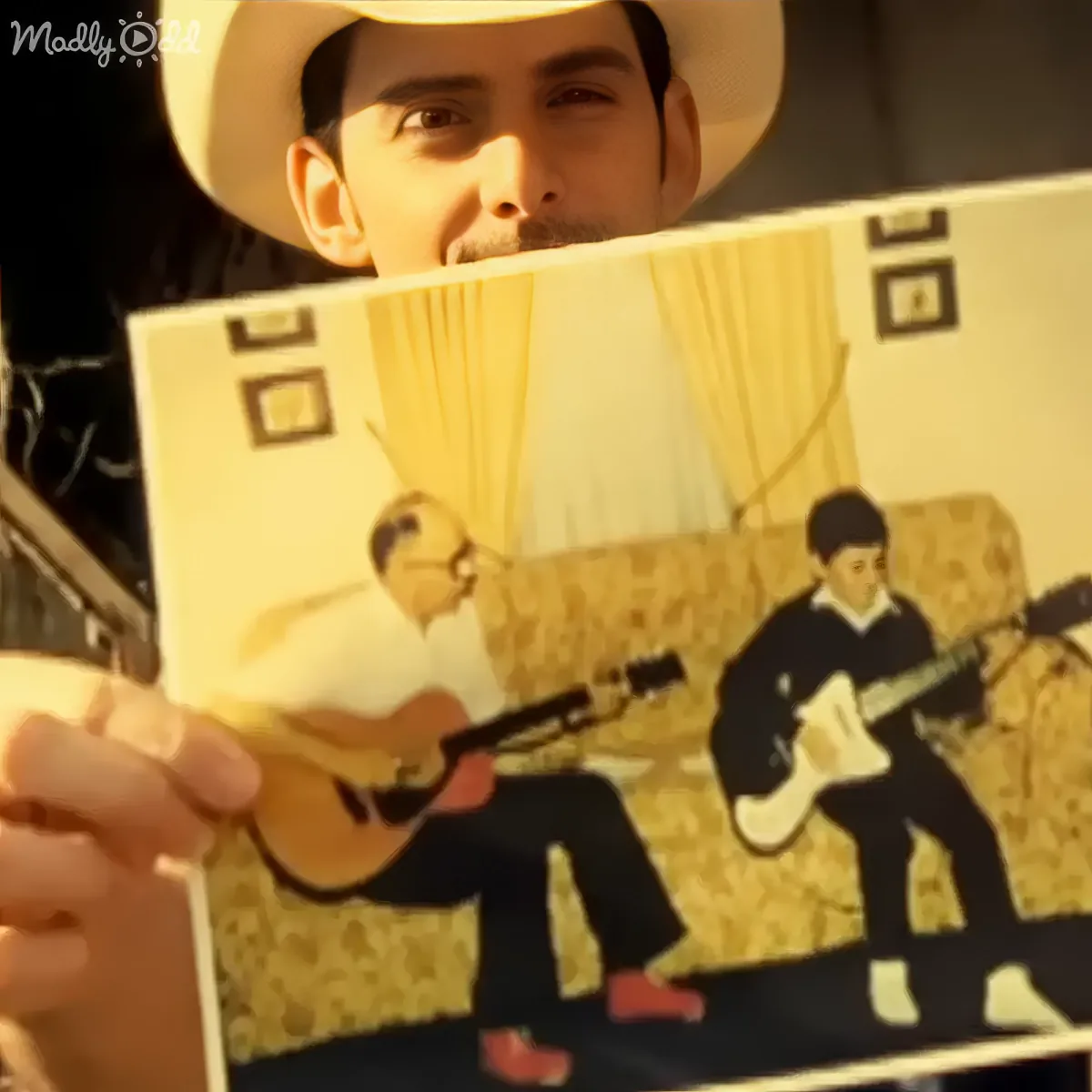 A person in a cowboy hat holds a record album featuring two guitarists.