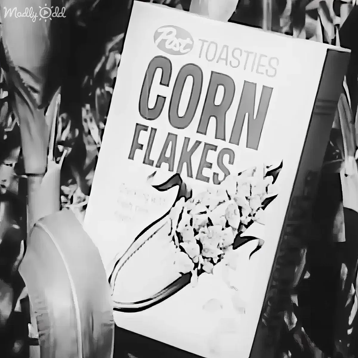 A black-and-white image shows a box of Post Toasties Corn Flakes with a bowl of cereal on it.