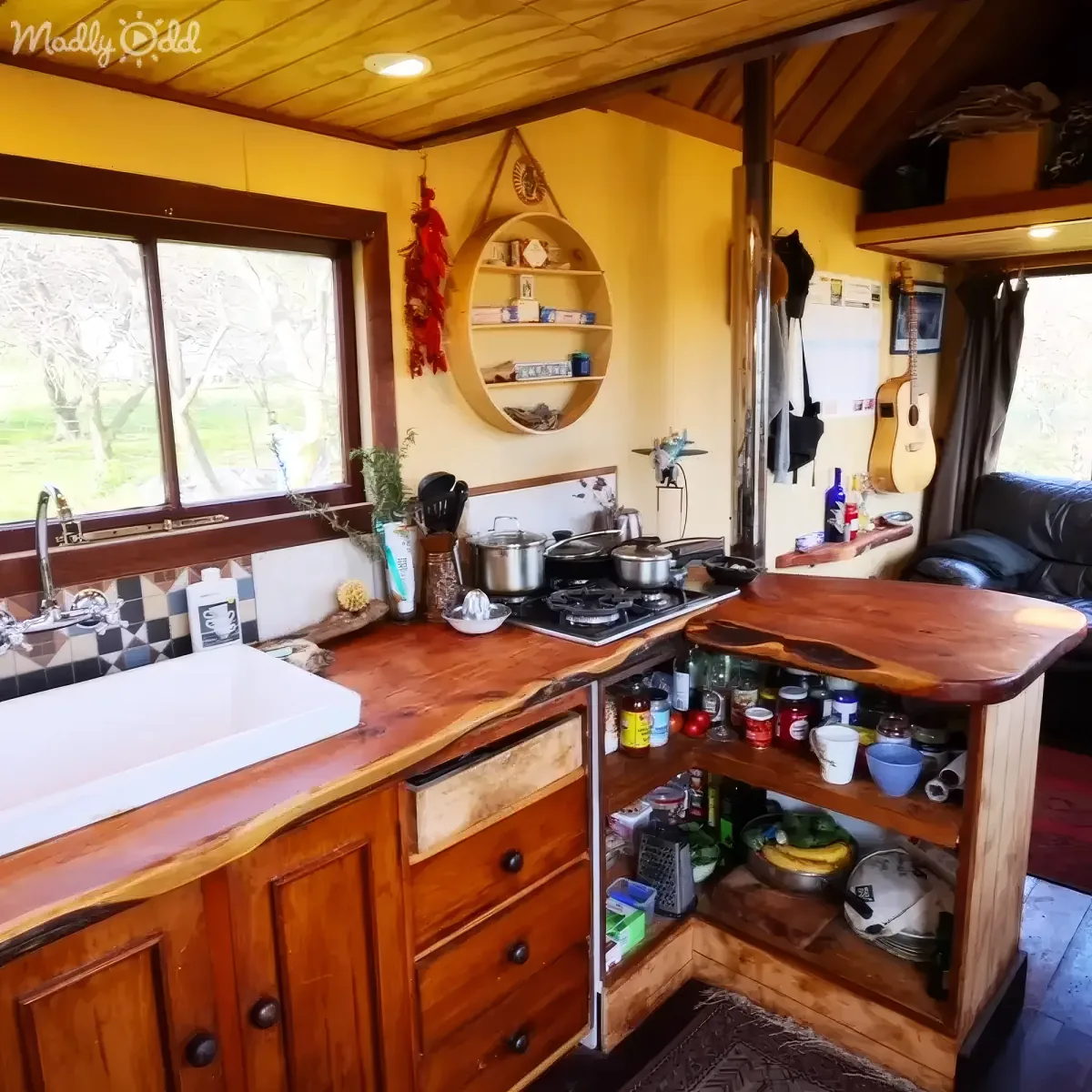 A cozy kitchen with wooden cabinets, a gas stove, and a rustic countertop, featuring various kitchen items and a view of...