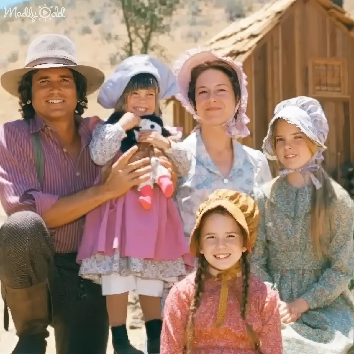 A family dressed in vintage attire poses together outdoors, smiling warmly.