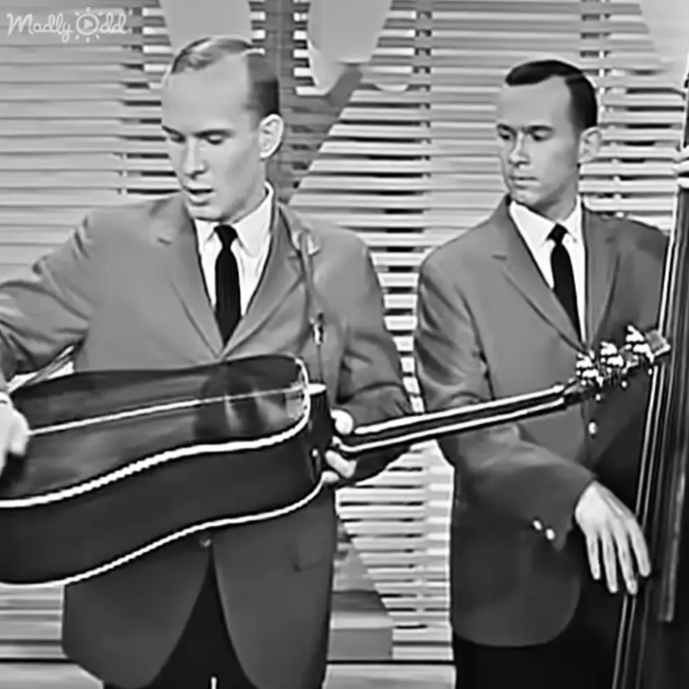 Two men in suits play a guitar and upright bass on stage.