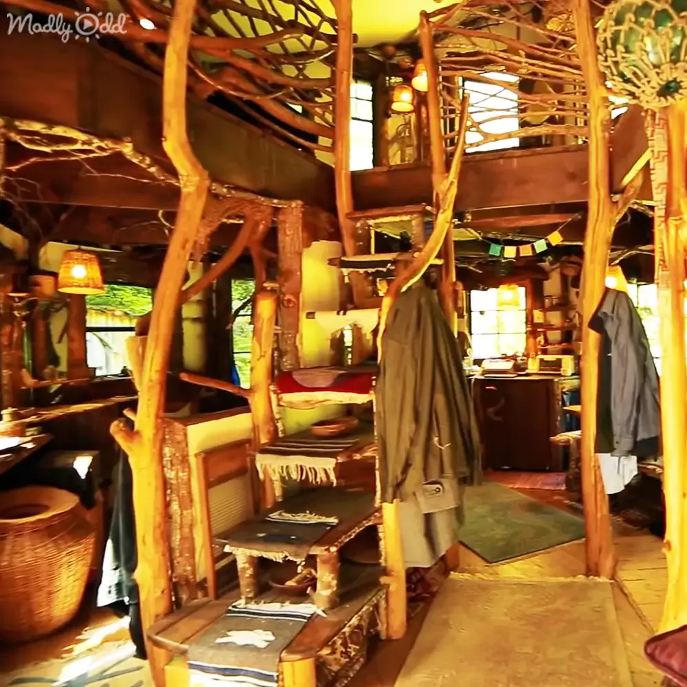 A rustic, treehouse-like interior with wooden beams, hanging lights, and a cozy, eclectic decor.