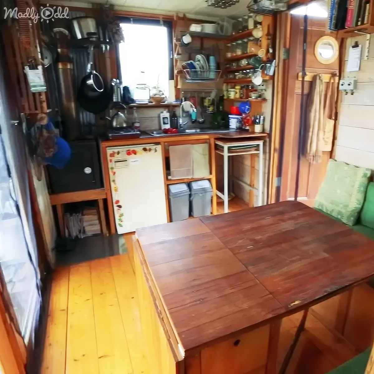 A cozy, compact kitchen with wooden furniture, a small fridge, and various kitchenware neatly arranged.