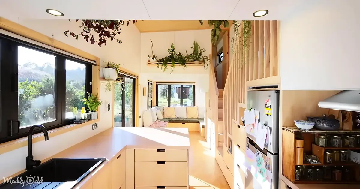 A cozy, well-lit kitchen with wooden cabinets, a sink, and a view of greenery through large windows.