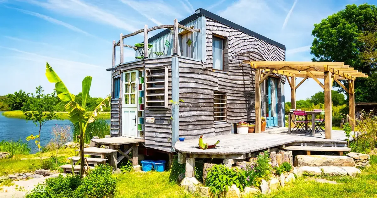 A rustic, wooden cabin with a porch, colorful doors, and a serene lakeside setting.