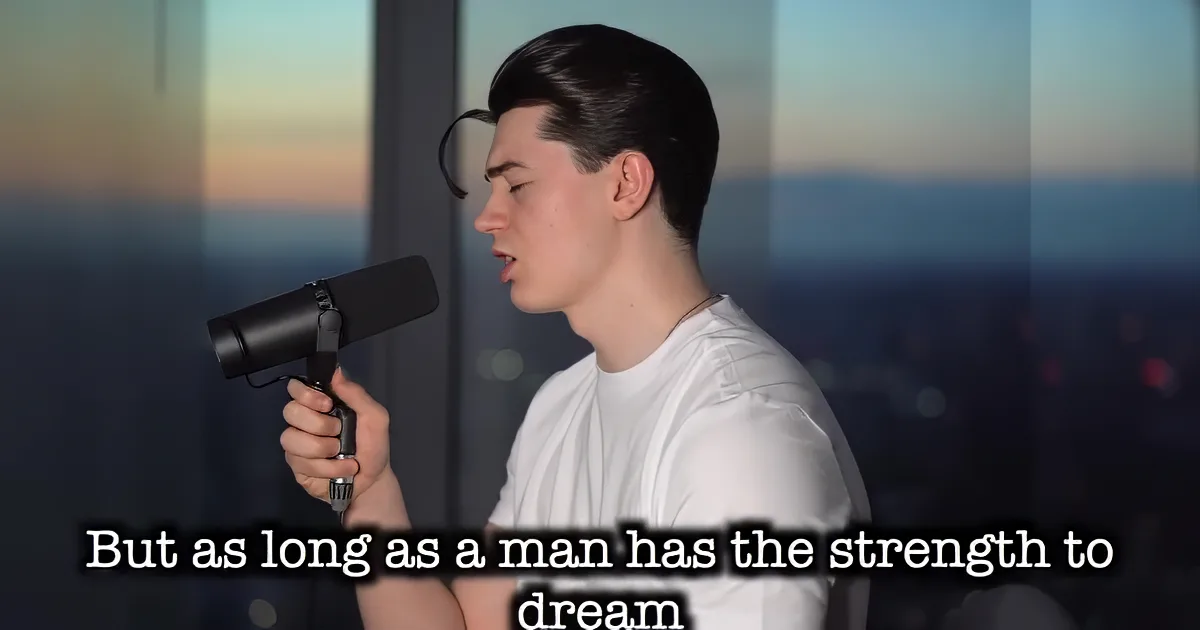 A person in a white shirt sings into a microphone, with a cityscape and bokeh lights in the background.