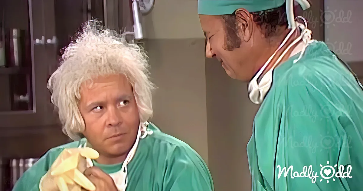 A person in green surgical scrubs holds a banana, while another in similar attire looks on.