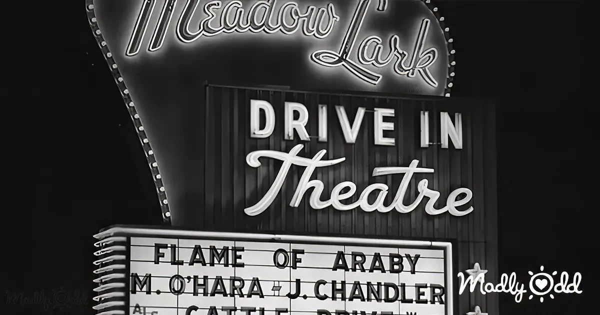 A vintage Meadow Lark Drive-In Theatre sign with a marquee displaying "Flame of Araby" and actors' names.