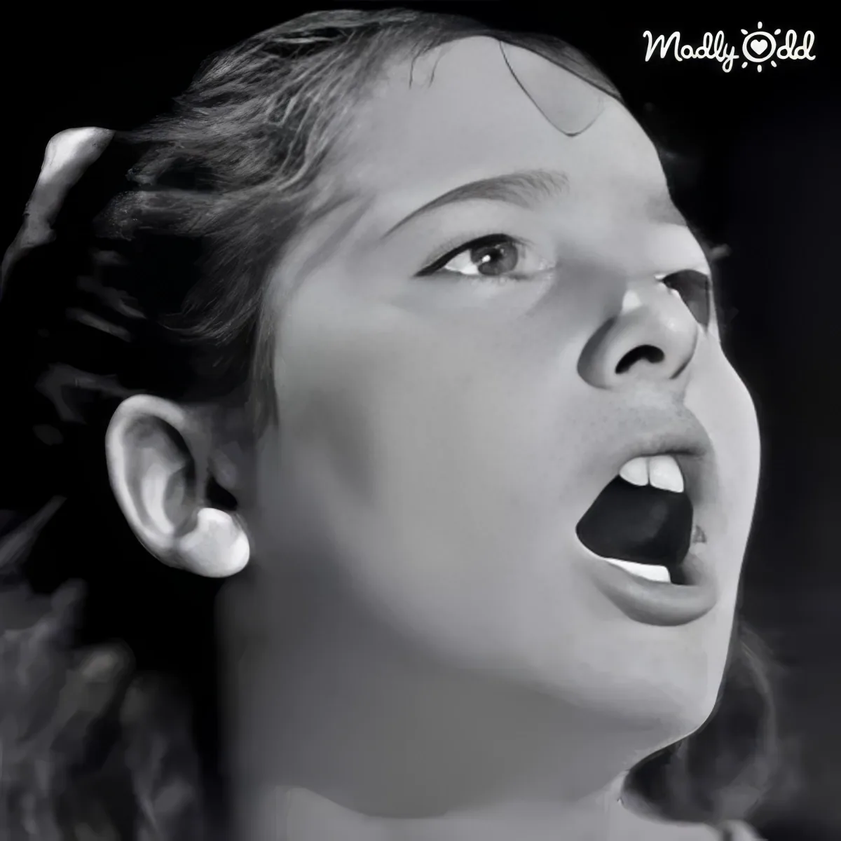 A young girl with her mouth open, looking upwards, in a black-and-white image.