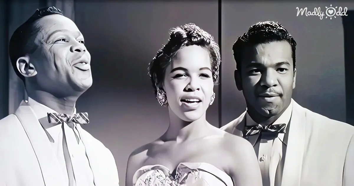 A black-and-white image shows three individuals in formal attire, possibly from a historical performance or event.
