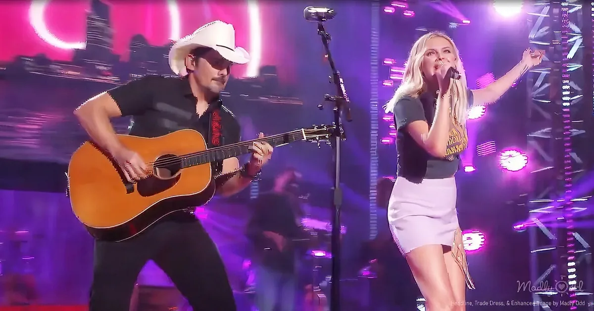 A man in a white cowboy hat plays guitar while a woman sings into a microphone on a stage with vibrant purple lights.