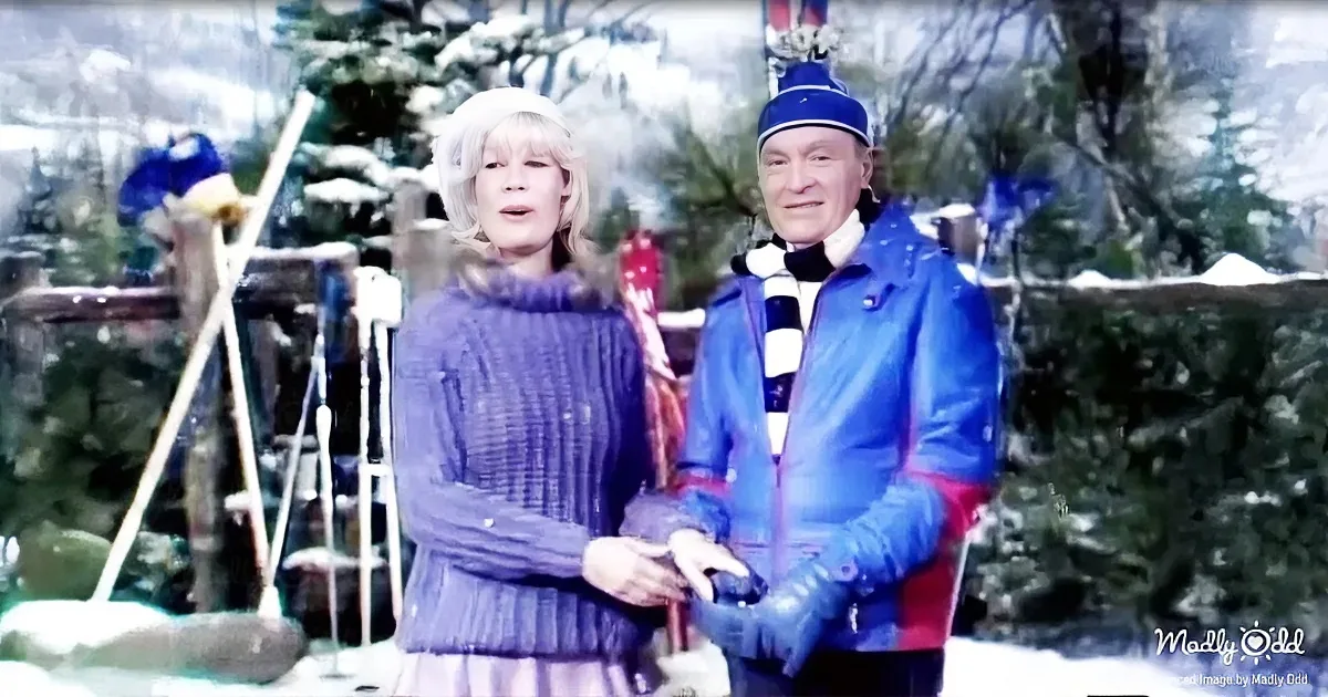 A woman in a purple sweater and a man in a blue jacket stand together in a snowy outdoor setting.