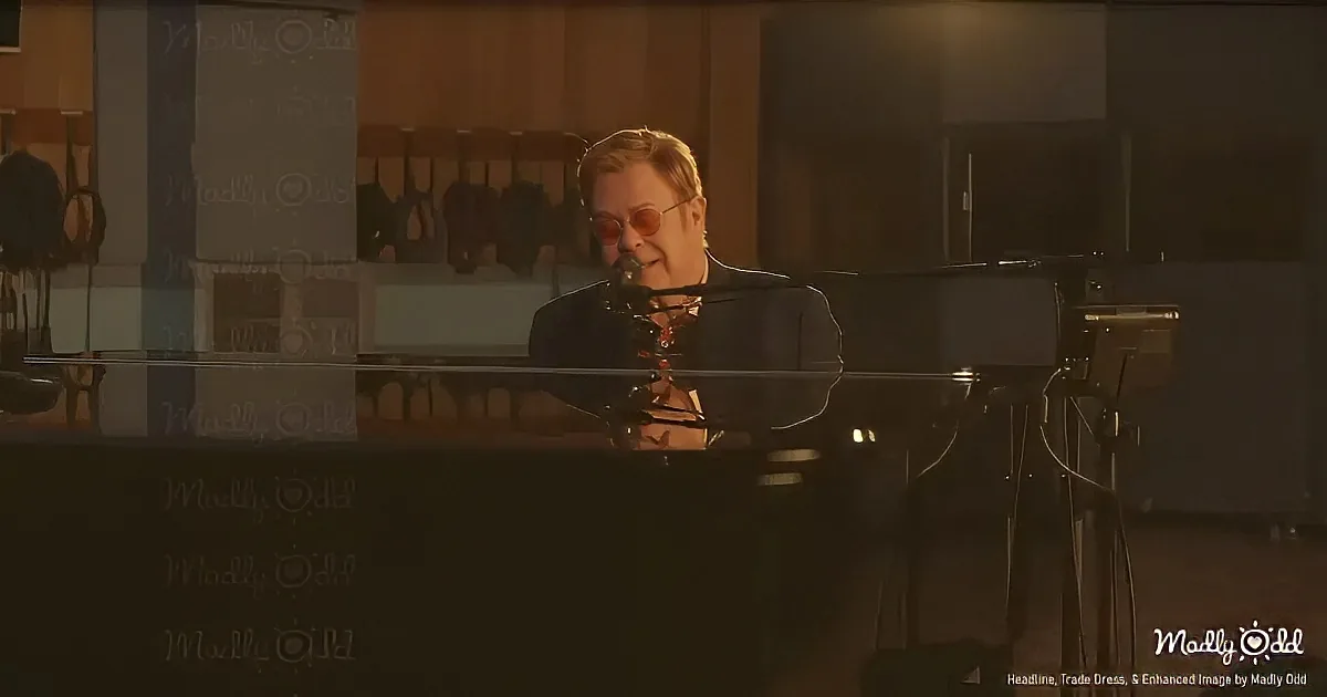 A person wearing sunglasses sits at a piano in a dimly lit room, surrounded by musical instruments.