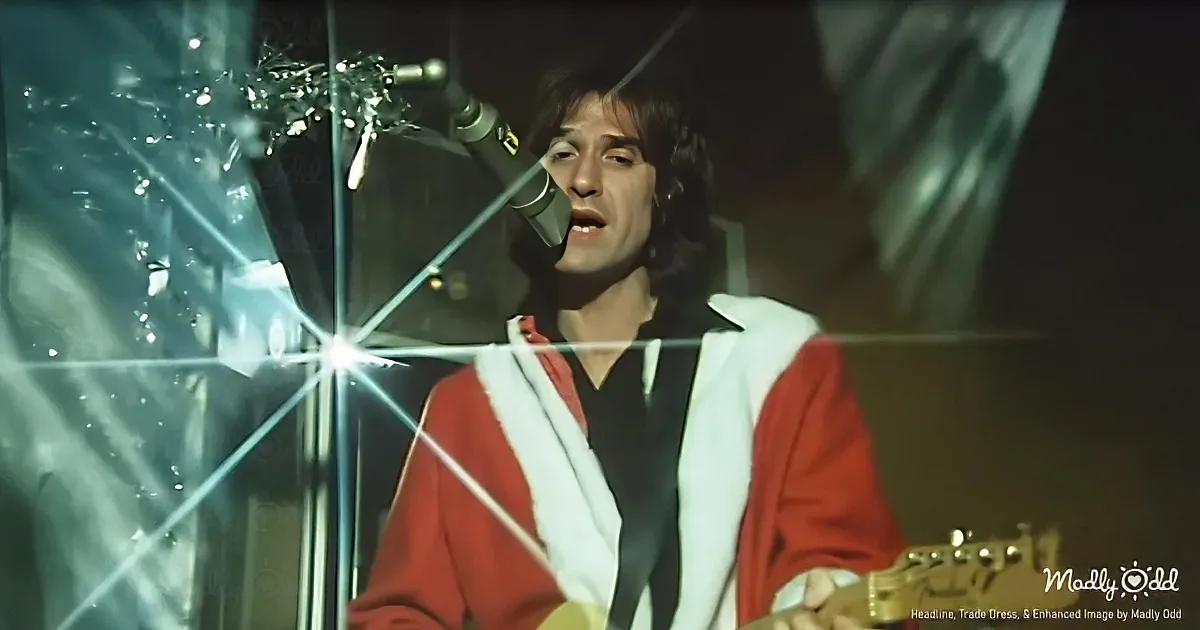 A person in a red and white outfit sings into a microphone, surrounded by shattered glass.